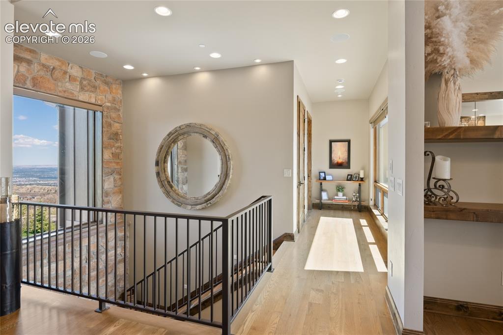 Image 21 of 50: Light-filled upper hallway with white oak flooring, custom iron railing, fl