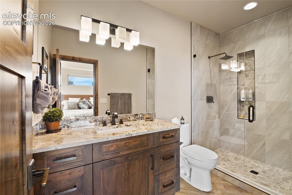 Image 42 of 50: Private ensuite featuring a full granite vanity, walk-in tile shower with p