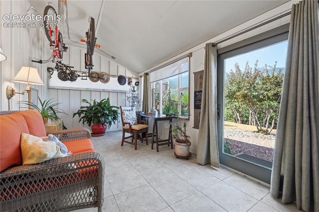Image 12 of 44: Private sun room off of garage area walks out to bak yard.  Tiled floor mak