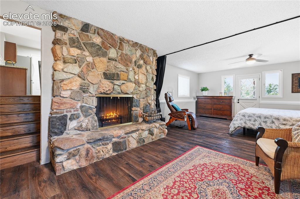Image 16 of 44: Lower level wood burning fireplace and view of stairs from main level.