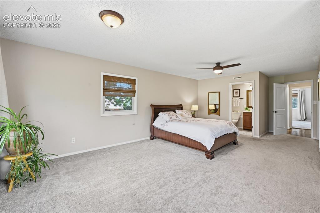 Image 26 of 44: Upper level primary bedroom with view towards the private full bathroom