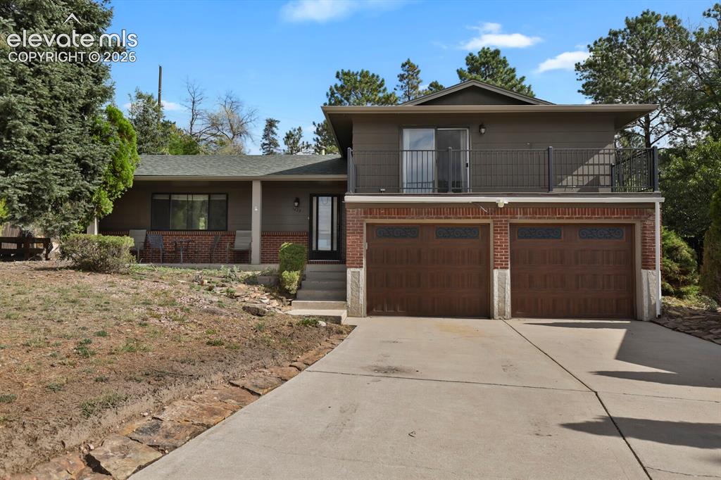 Caption: Exterior featuring a two-car garage with brick accents, an upper-level balcony with metal railing, a