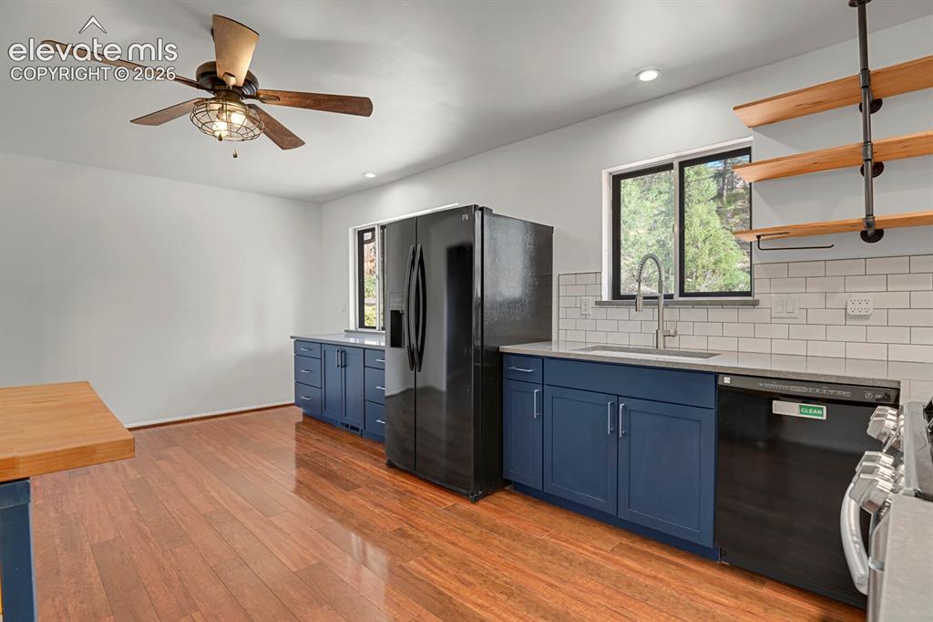 Image 10 of 35: Kitchen featuring wood-finish flooring, dark blue cabinetry, white subway t