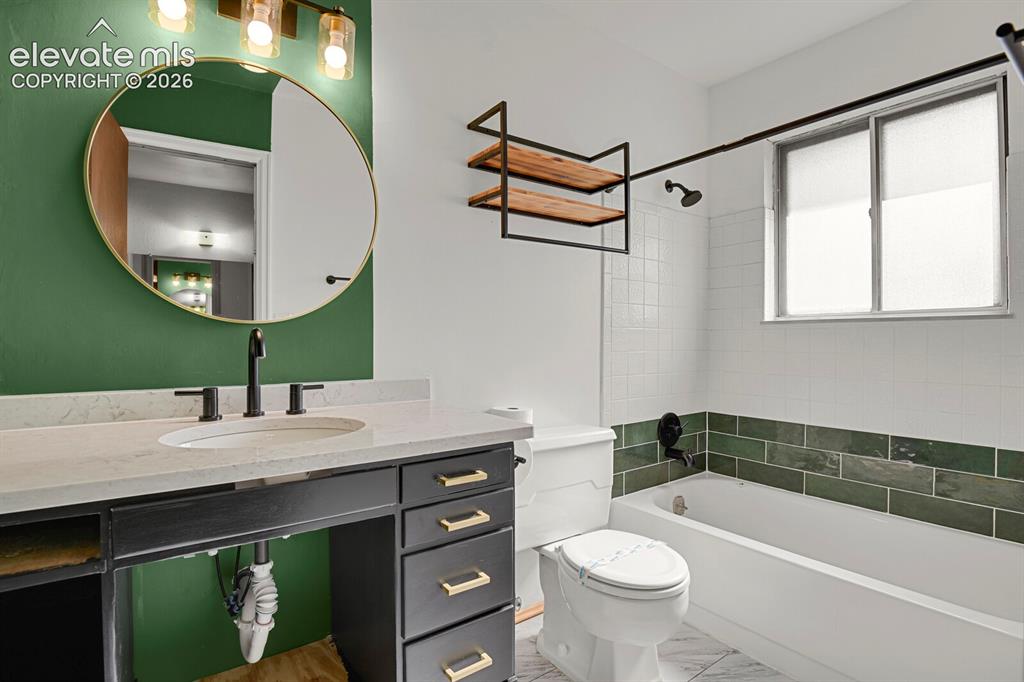 Image 14 of 35: Bathroom featuring an oval mirror, a vanity with a light-toned countertop,