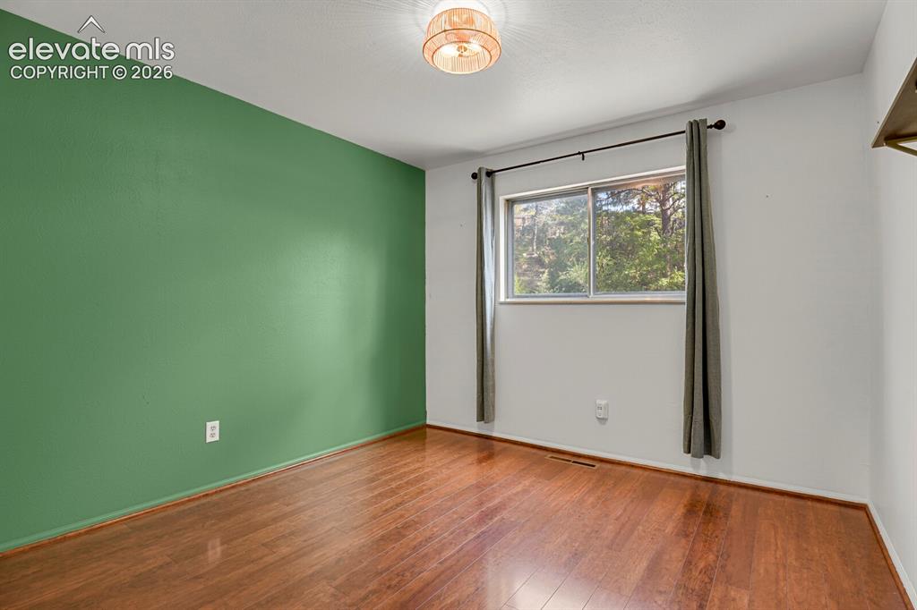 Image 15 of 35: Wood-finish flooring, accent wall, ceiling-mounted light fixture, and windo