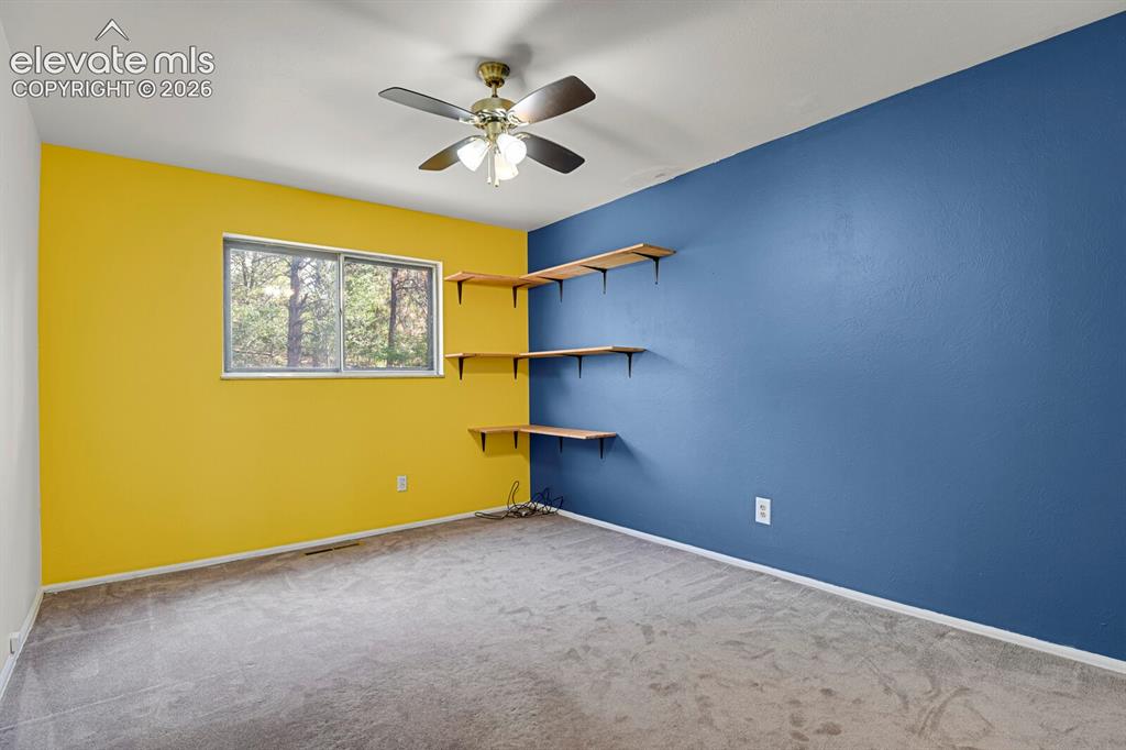 Image 18 of 35: Room featuring a ceiling fan, a window with outdoor scenery, built-in shelv