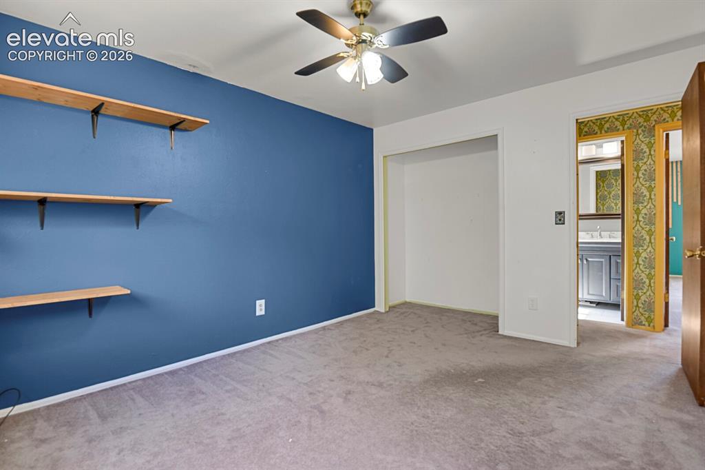 Image 19 of 35: Ceiling fan with light fixture, carpeted flooring, built-in shelving, and a