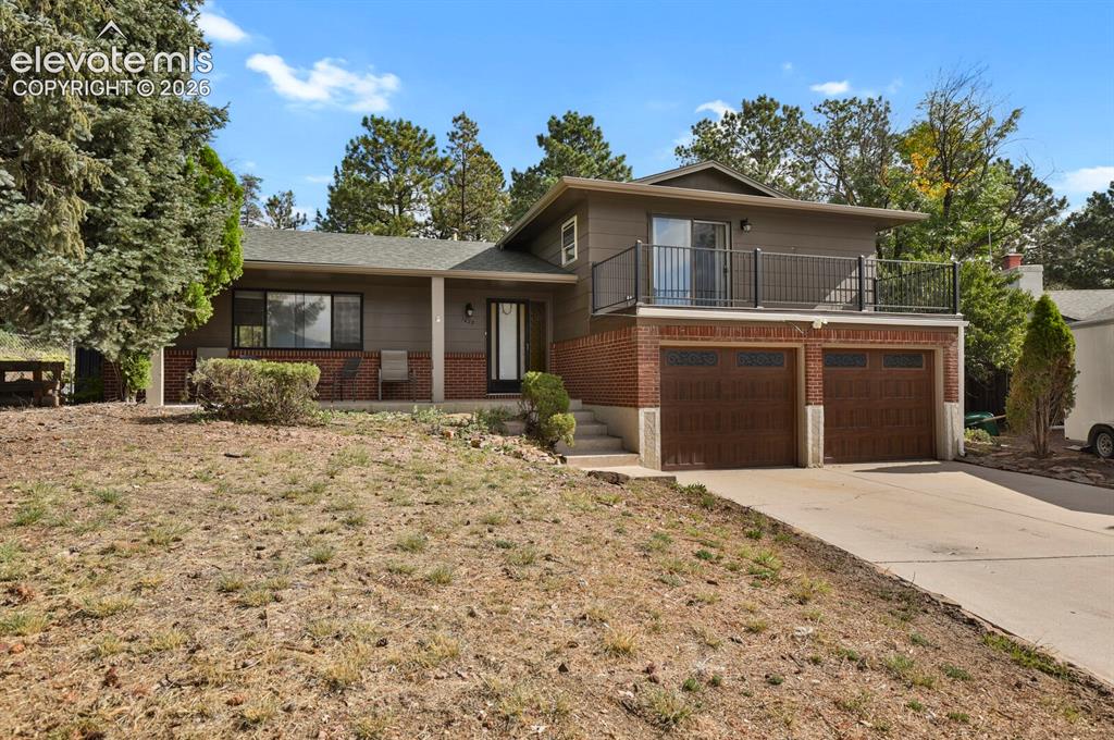 Image 2 of 35: Split-level exterior with brick accents, an upper-level balcony with metal