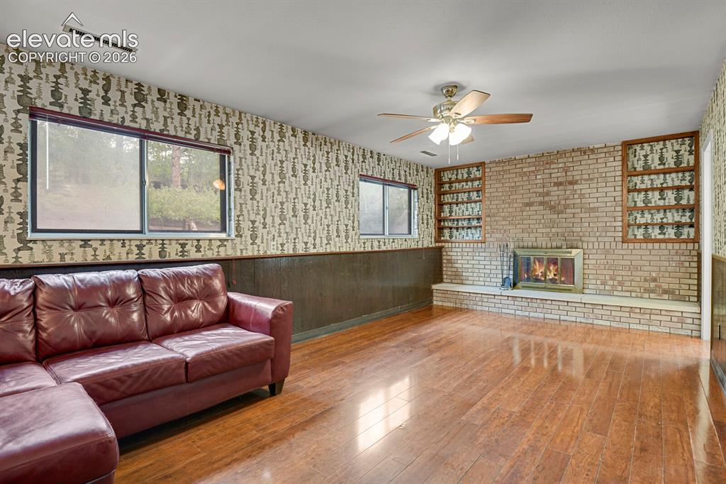 Image 20 of 35: Wood-finish flooring with a brick fireplace, built-in shelving, and a ceili