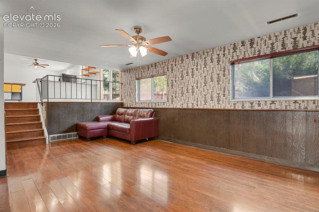 Image 22 of 35: Wood-finish flooring throughout, complemented by wood paneling and patterne