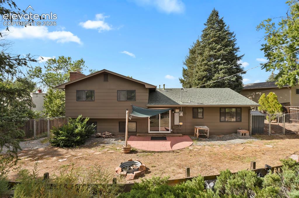 Image 24 of 35: Rear exterior featuring a brick patio, sliding glass door access, and a slo