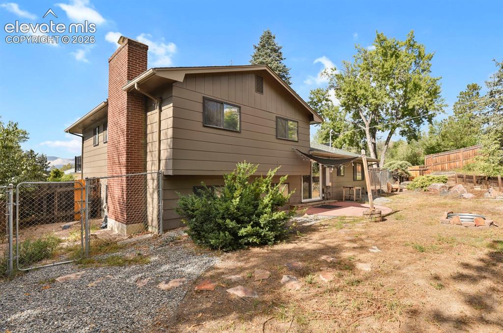 Image 25 of 35: Exterior featuring a brick chimney, a patio with a partial awning, and a te