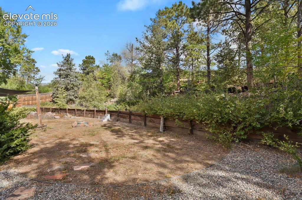 Image 26 of 35: Expansive outdoor space featuring a wood retaining wall, gravel landscaping