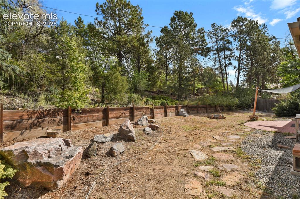Image 27 of 35: Expansive outdoor space featuring a wood retaining wall, natural rock lands