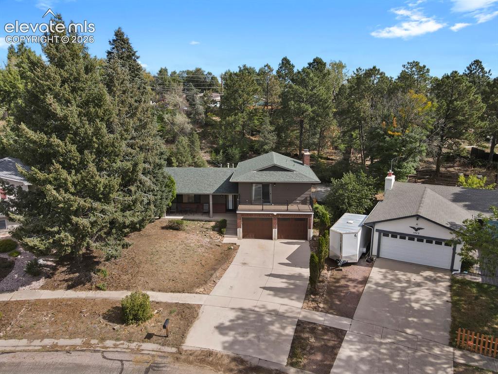 Image 29 of 35: Brown exterior with a green shingle roof, attached two-car garage, and a co