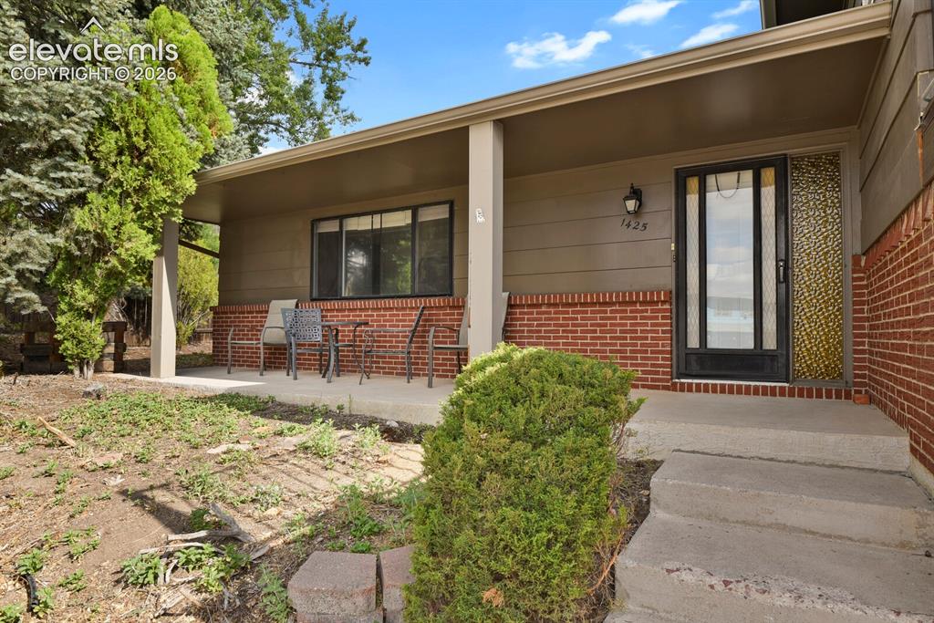 Image 4 of 35: Covered front porch with brick and siding facade, concrete steps, and a gla