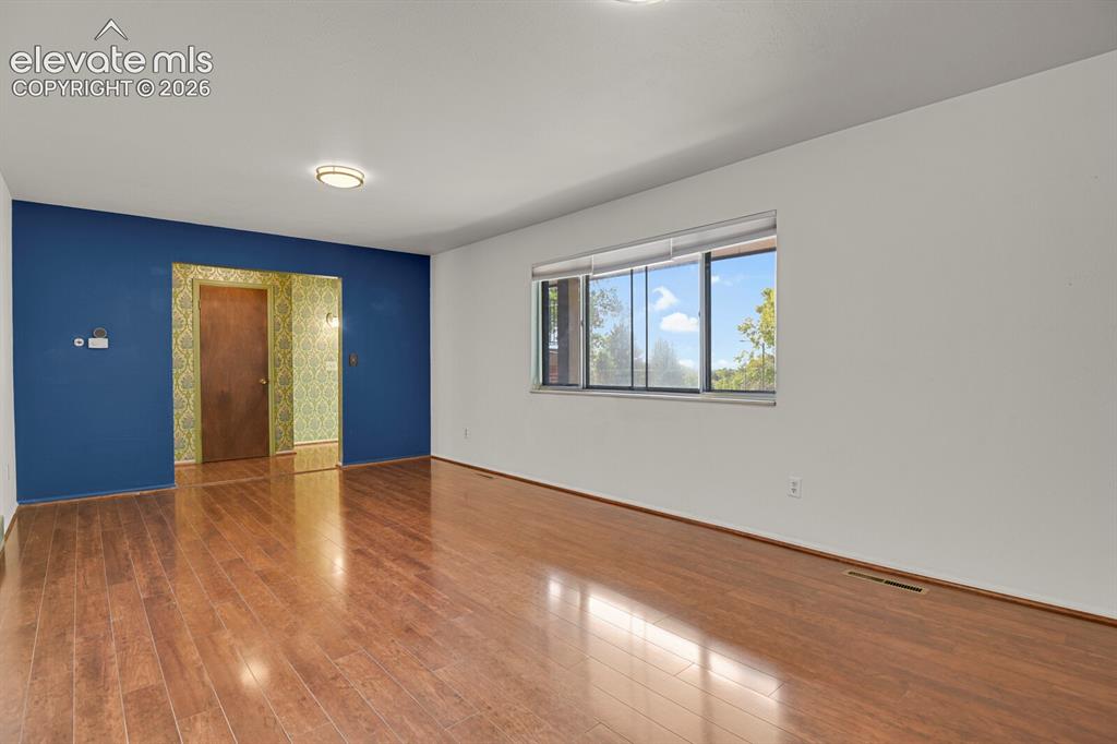 Image 6 of 35: Expansive room featuring wood-finish flooring, a large window, a ceiling-mo