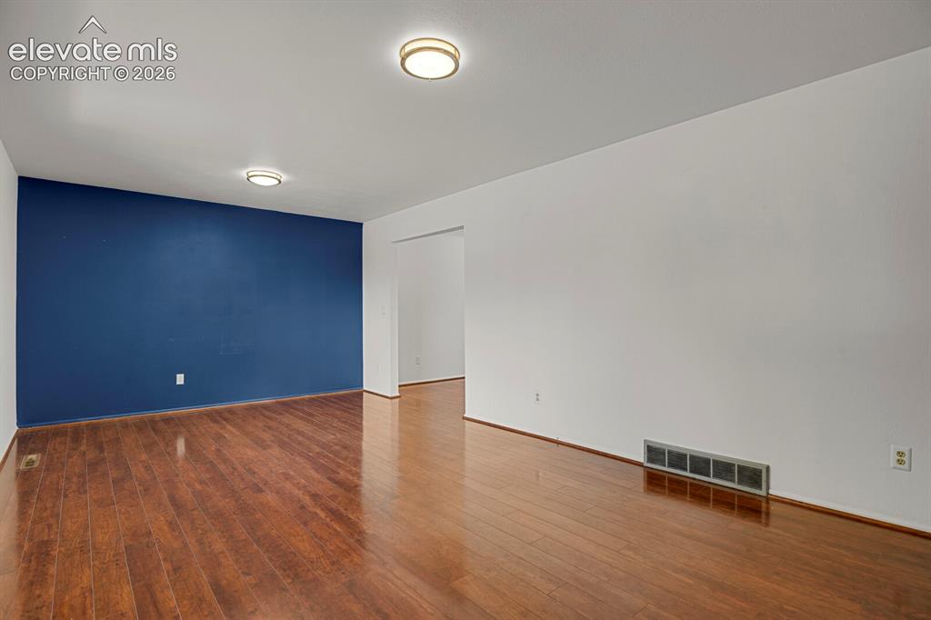 Image 7 of 35: Wood-finish flooring with a deep blue accent wall