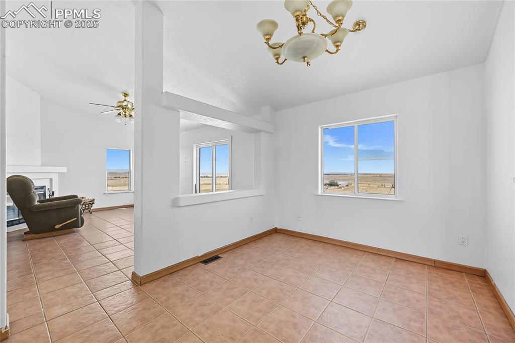 Image 14 of 28: Spare room with light tile patterned floors, a chandelier, a fireplace, a c