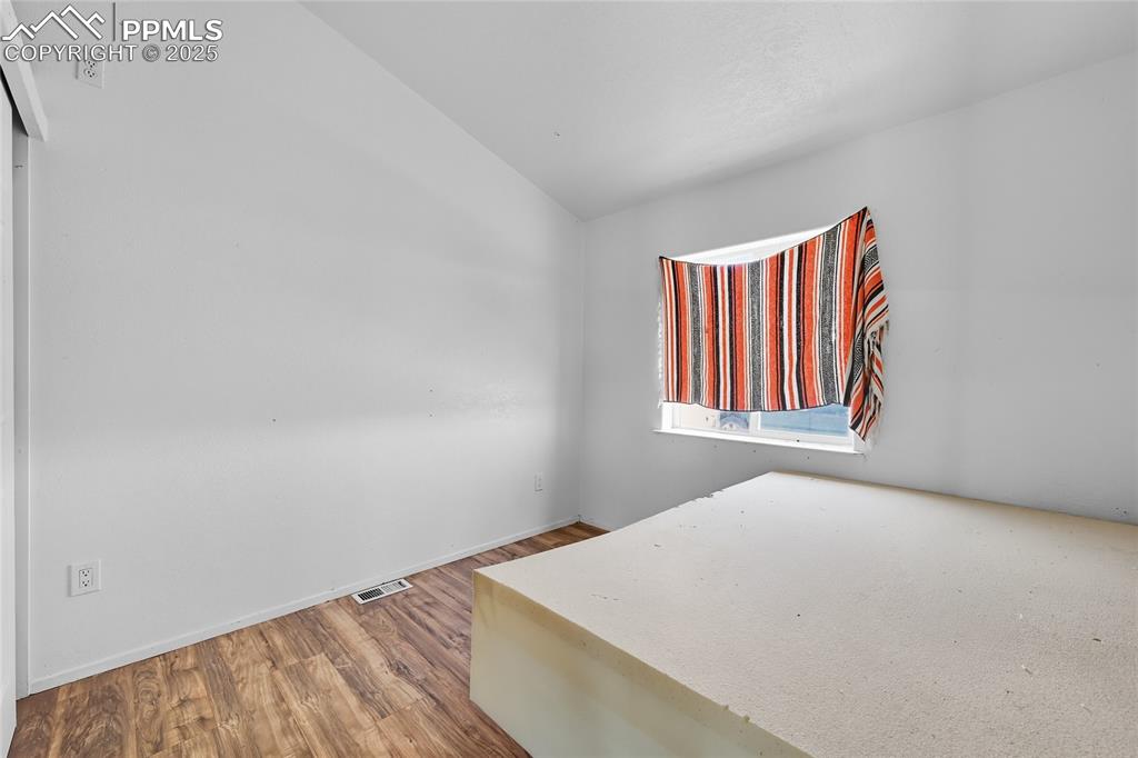 Image 19 of 28: Unfurnished room featuring lofted ceiling and wood finished floors