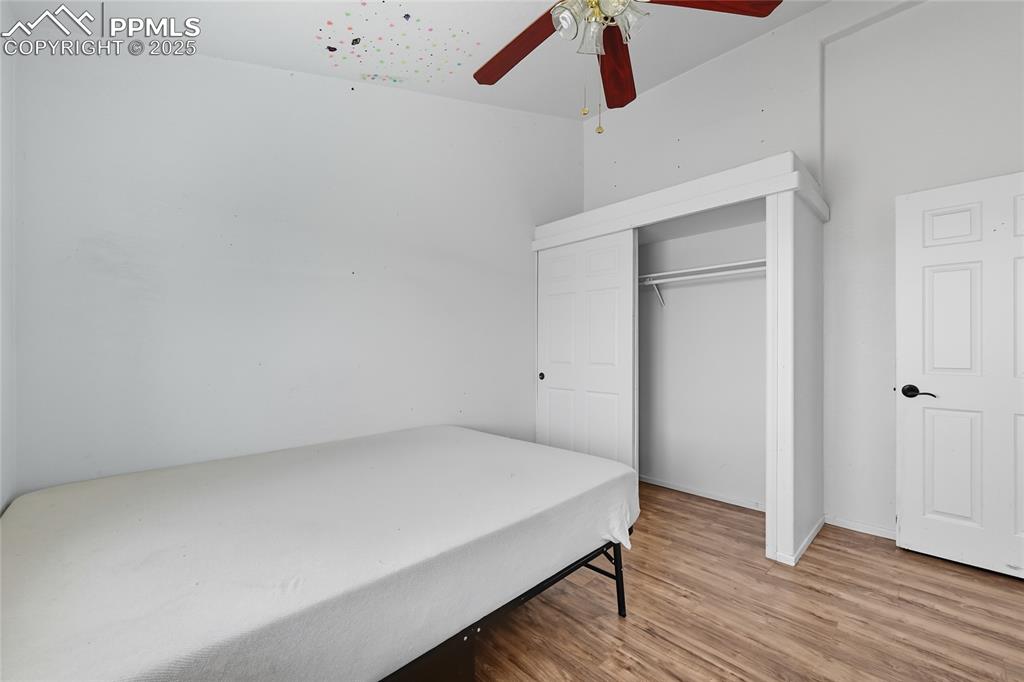 Image 23 of 28: Bedroom with light wood finished floors, a ceiling fan, and a closet