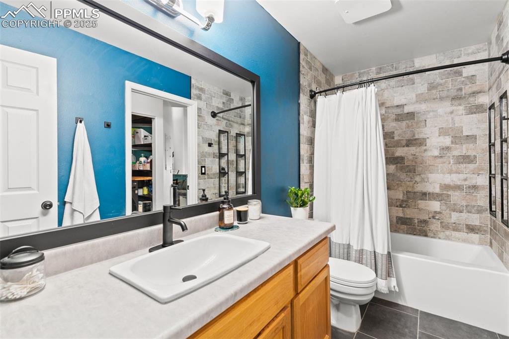 Image 10 of 27: Bathroom with shower / bath combo, vanity, and dark tile patterned flooring