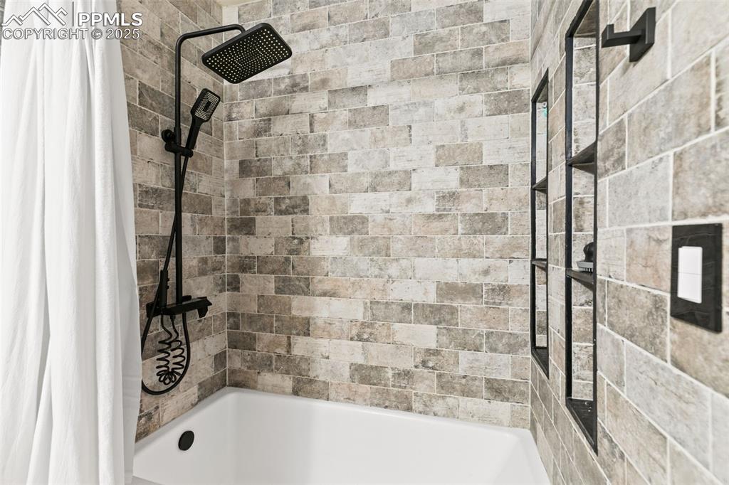 Image 11 of 27: Bathroom with shower / bath combination with curtain