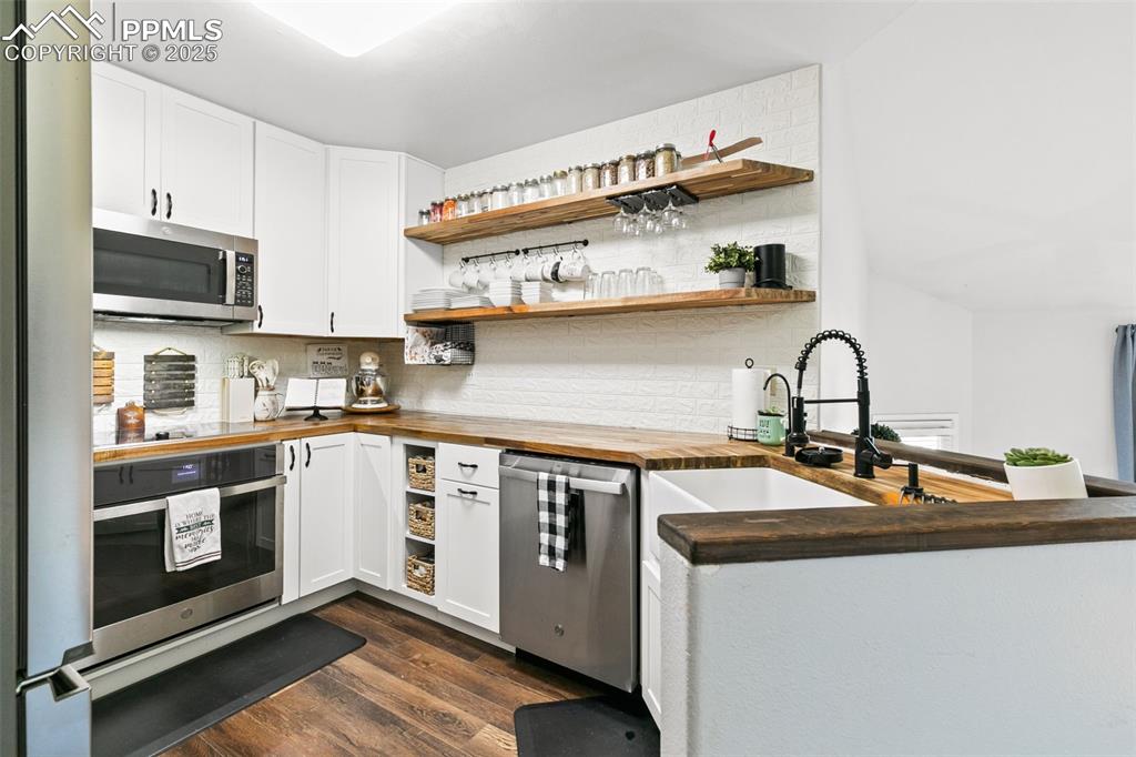 Image 14 of 27: Kitchen with open shelves, butcher block countertops, dark wood finished fl