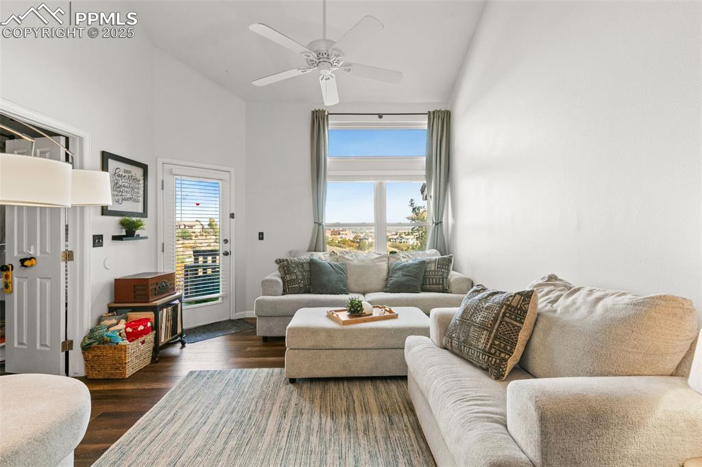 Image 18 of 27: Living area featuring dark wood-style flooring, a towering ceiling, and a c