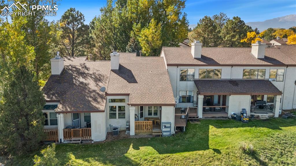 Image 24 of 27: Back of property featuring a chimney, stucco siding, a yard, and a deck