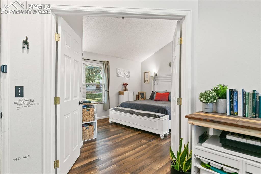 Image 6 of 27: Bedroom with a textured ceiling, dark wood-style floors, and lofted ceiling
