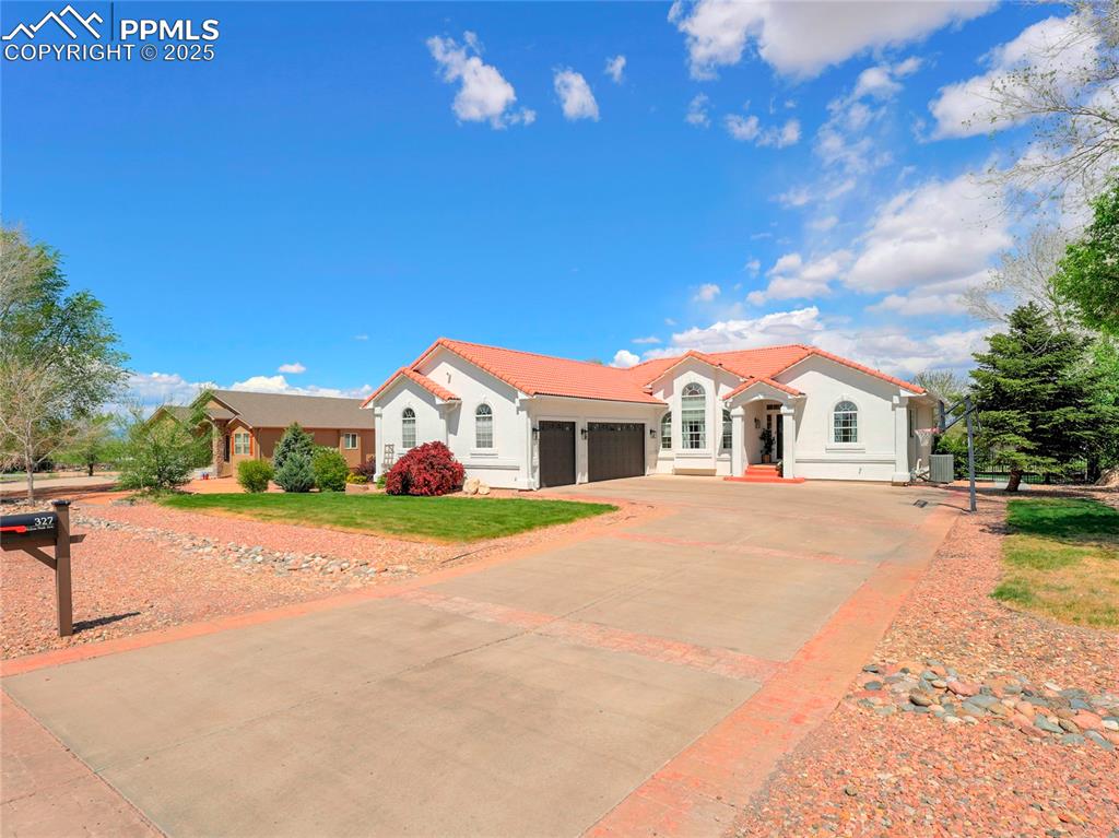 Caption: Mediterranean / spanish-style home with a garage, stucco siding, concrete driveway, a tiled roof, an