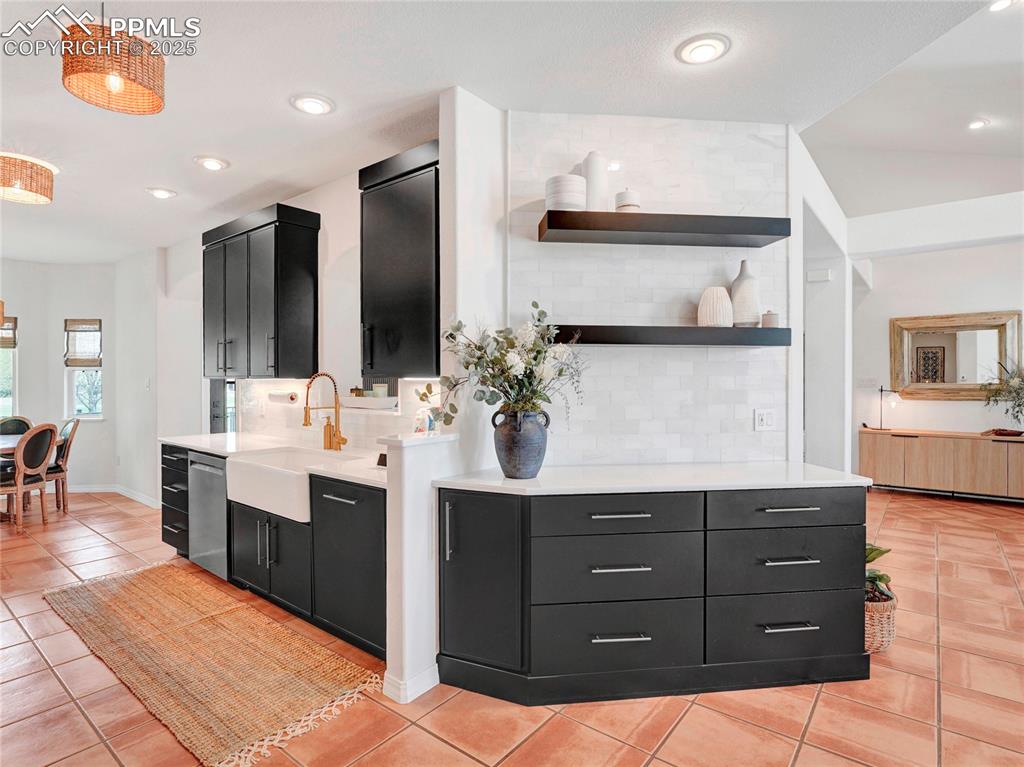 Image 10 of 44: Kitchen featuring dark cabinetry, dishwasher, a sink, light countertops, an