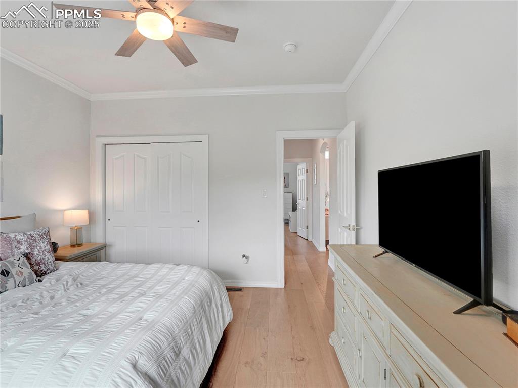 Image 23 of 44: Bedroom featuring ornamental molding, light wood-style floors, a closet, ba