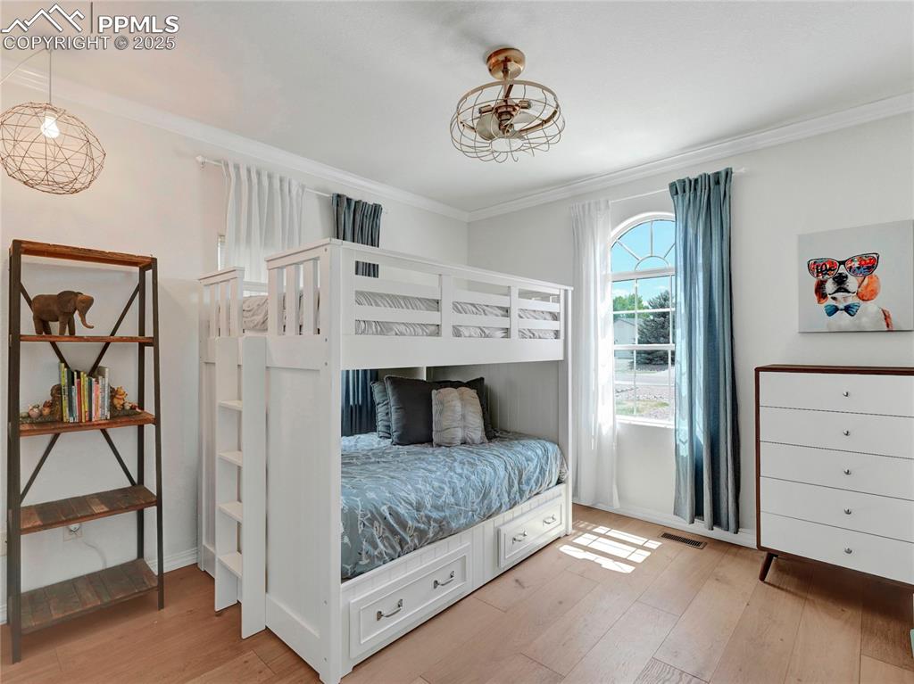Image 25 of 44: Bedroom with ornamental molding, light wood-type flooring, and baseboards
