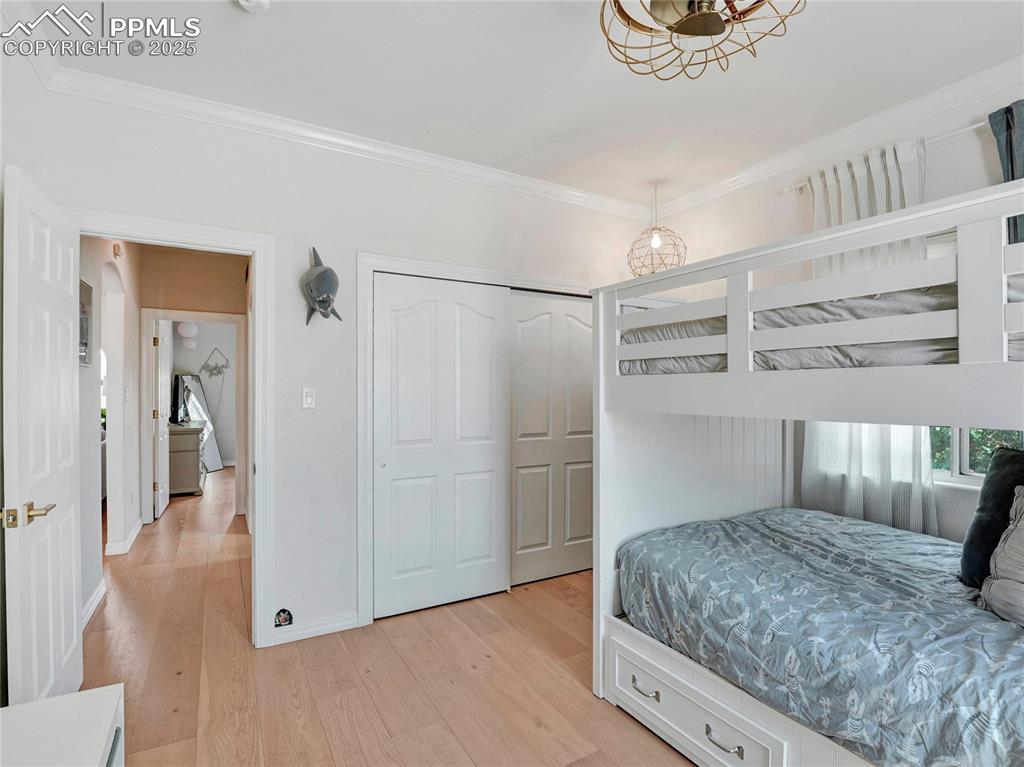 Image 26 of 44: Bedroom with crown molding, light wood finished floors, a chandelier, baseb
