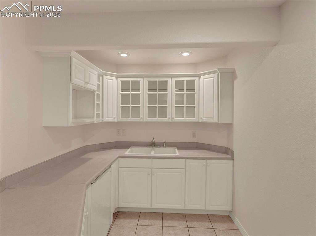 Image 32 of 44: Kitchen with a sink, white cabinetry, light tile patterned floors, light co