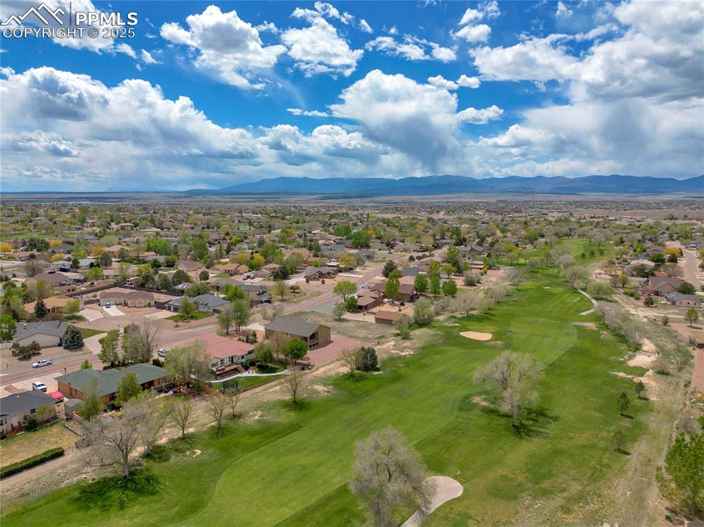 Image 44 of 44: Aerial view of residential area with a mountainous background and a local g