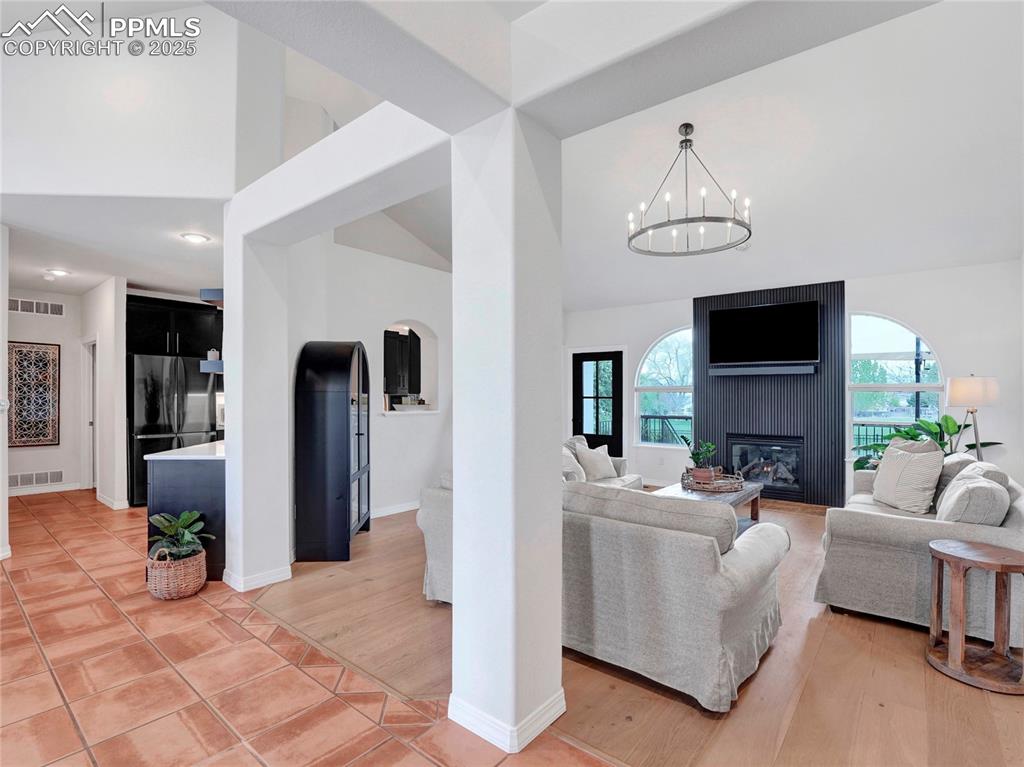 Image 7 of 44: Living room with high vaulted ceiling, a fireplace, plenty of natural light