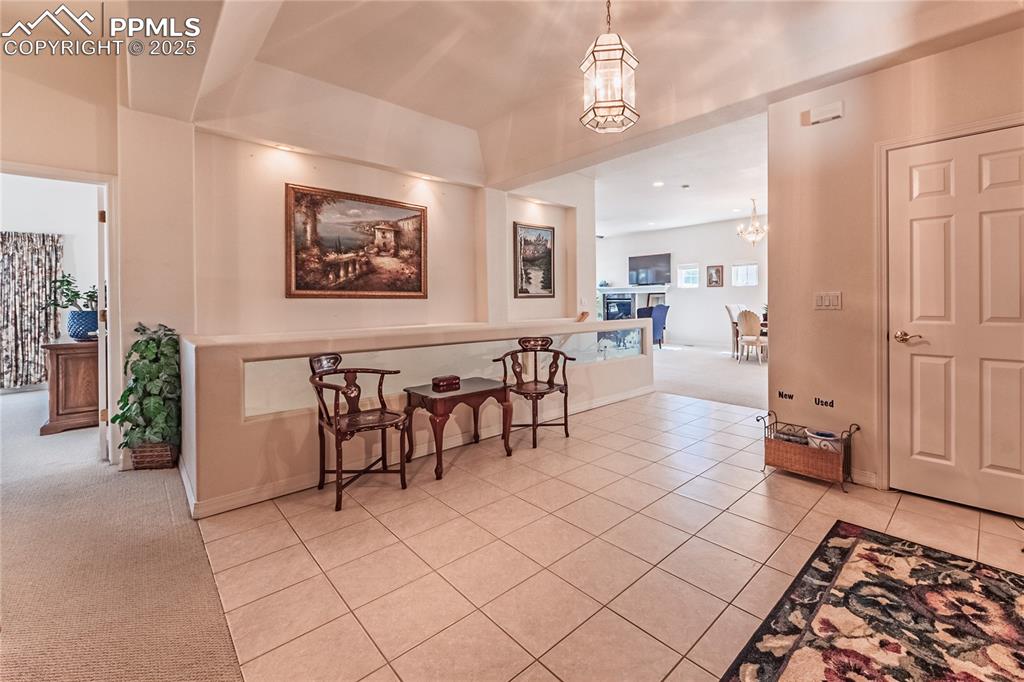 Image 11 of 49: Dining space with light carpet, light tile patterned floors, and a chandeli