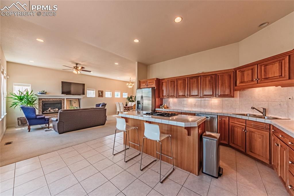 Image 13 of 49: Kitchen with tile counters, light carpet, light tile patterned floors, appl