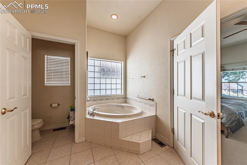 Image 18 of 49: Ensuite bathroom featuring toilet, a bath, tile patterned flooring, and vis