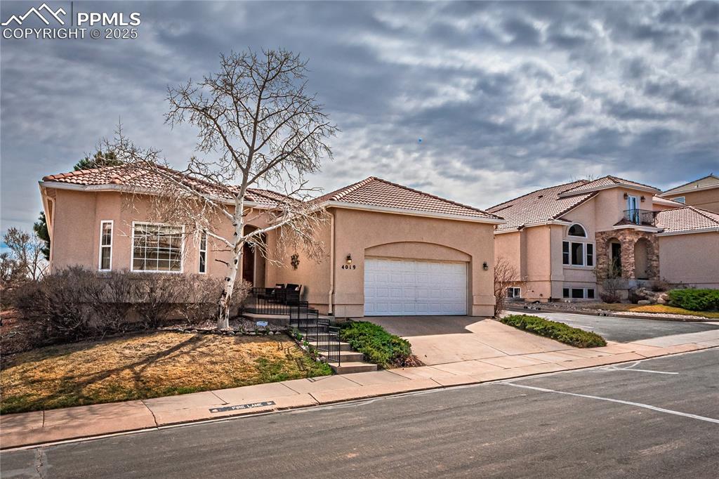 Image 2 of 49: Mediterranean / spanish home featuring stucco siding, a tiled roof, a garag