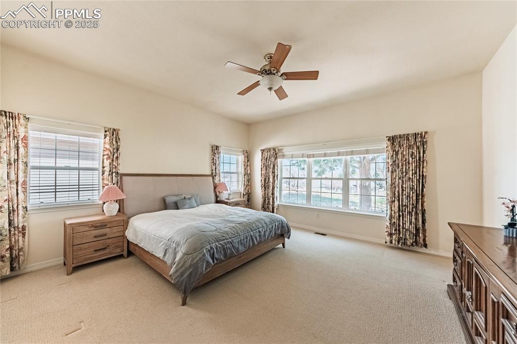 Image 20 of 49: Bedroom featuring light colored carpet, baseboards, a ceiling fan, and visi
