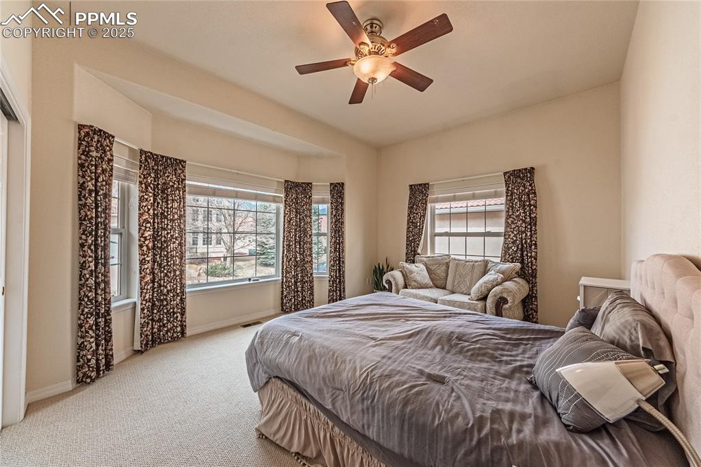 Image 22 of 49: Carpeted bedroom featuring visible vents, baseboards, and a ceiling fan