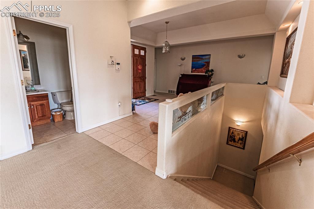 Image 25 of 49: Stairs with visible vents, carpet, tile patterned flooring, and baseboards