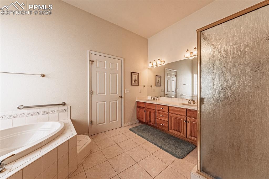 Image 27 of 49: Bathroom with a bath, a shower with door, a sink, tile patterned floors, an