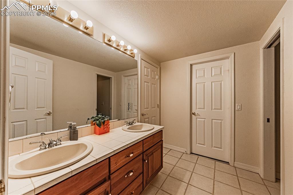 Image 35 of 49: Full bath featuring tile patterned floors, double vanity, baseboards, and a
