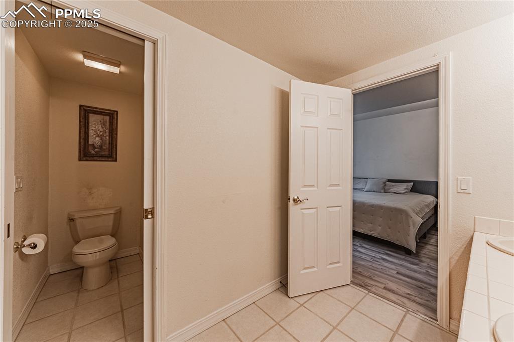 Image 37 of 49: Ensuite bathroom with ensuite bathroom, a textured ceiling, tile patterned 