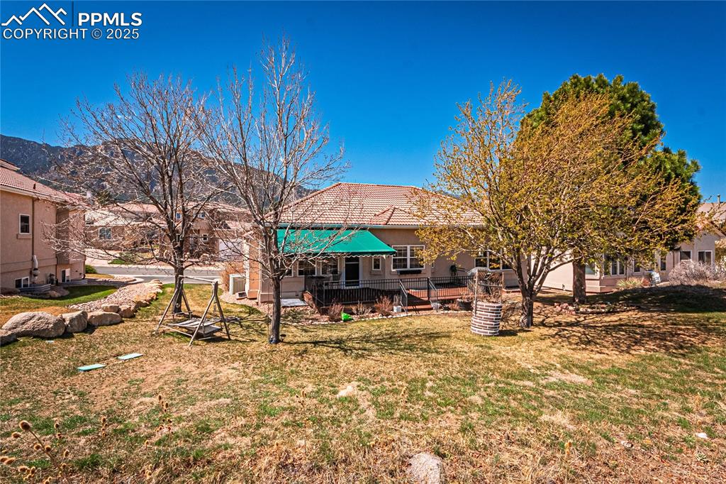 Image 40 of 49: Back of property featuring a tiled roof, stucco siding, and a lawn